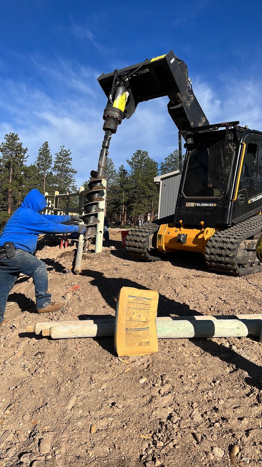 Hydraulic auger drilling fence post holes on a new build