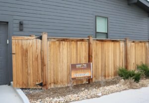 Neat stained cedar fence along a sidewalk with a Golden Stain yard sign